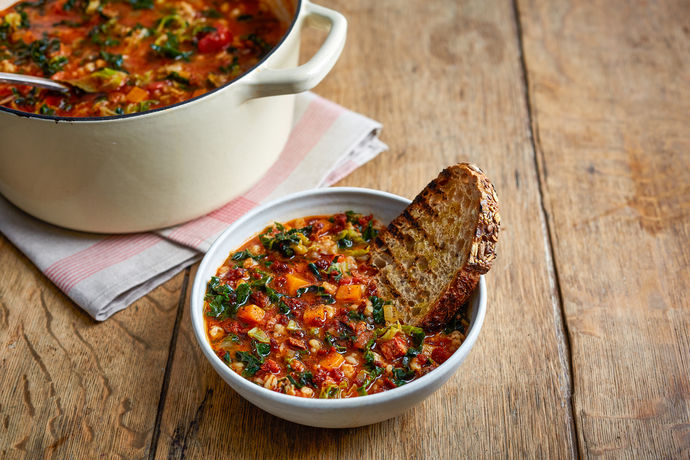 Bowl of hearty veg soup with toasted bread and a batch on the side as a cheap lunch idea