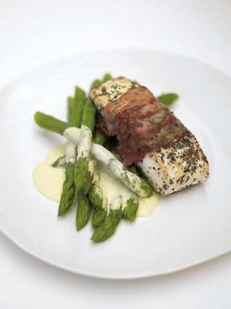 Delicious roasted white fish wrapped in smoked bacon with lemon mayonnaise and asparagus
