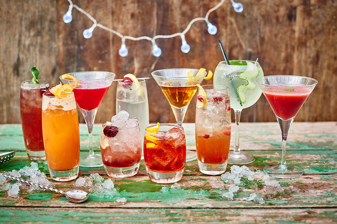 an array of cocktails with ice and fruit garnishes