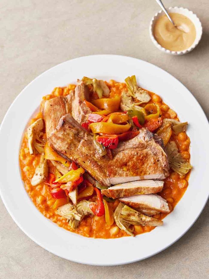 Plate of pork tenderloin on a bed of tomatoes and peppers