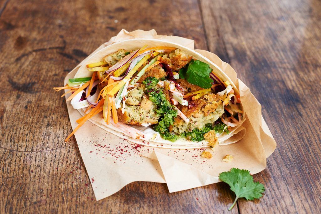 A wrapped up soft tortilla with colourful veg and coriander