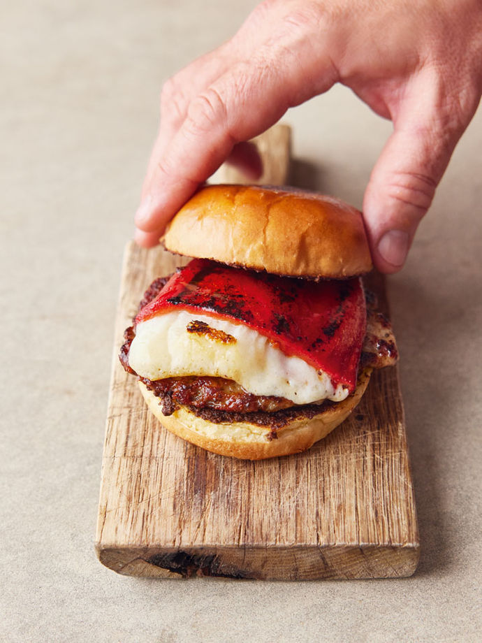 A sausage patty, manchego cheese and roasted red pepper in between two halves of a bun